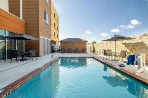 a swimming pool with chairs and a table and a building at Fairfield Inn & Suites by Marriott West Monroe in West Monroe