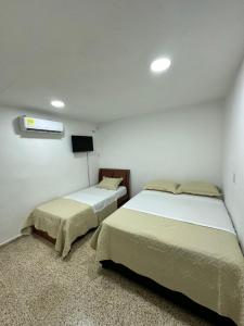 a bedroom with two beds and a tv on the wall at Hotel H&H in Cartagena de Indias