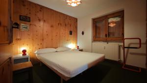 una camera con un letto bianco e una parete in legno di La Betulla a Verrand