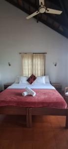 a bedroom with a large bed with a ceiling fan at Nadhi Teera Riverside Stay in Kushālnagar