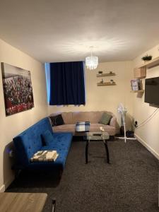 a living room with a blue couch and a tv at Airrose two bed apartment in Wolverhampton