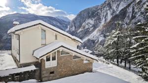 una casa ricoperta di neve con montagne sullo sfondo di La Betulla a Verrand