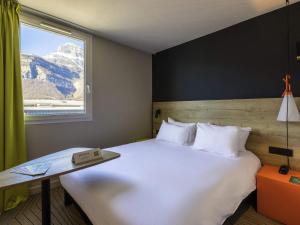 a bedroom with a large white bed with a window at Ibis Styles Crolles Grenoble A41 in Crolles +59 photos
