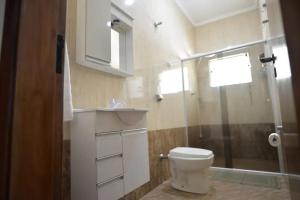 ein Badezimmer mit Toilette und Glasdusche in der Unterkunft Casa Familiar Morada in Aparecida + 23 Fotos