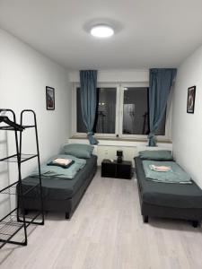 Ferienwohnung Monteurwohnung Business Appartement Langenfeld في Gladbach: سريرين في غرفة مع ستائر زرقاء