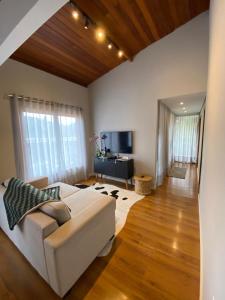 ein Wohnzimmer mit einem weißen Sofa und einem Fernseher in der Unterkunft Casa da Rota dos Ipês in Domingos Martins