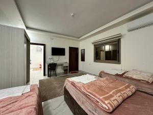 Un dormitorio con dos camas y un escritorio y un televisor. en Mountain Echo Inn, en Taiyiba