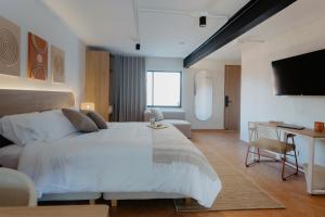 a bedroom with a large white bed and a tv at Pranik Living Wellness Coliving Laureles Medellin in Medellín
