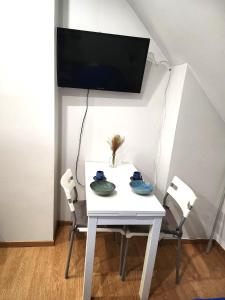 a white table and chairs with a tv on the wall at Studio place Victor Hugo in La Celle-sous-Gouzon