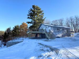 a large house in the snow with snow covered grounds at 2T Bethlehem Retreat with Stunning Sunset Views in the Heart of the White Mountains in Bethlehem