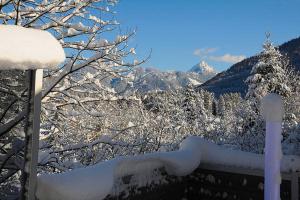 een hek bedekt met sneeuw met bergen op de achtergrond bij Ferienhaus Alpenflair bei Schliersee in Schliersee
