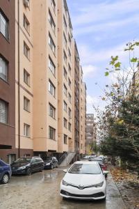 a car parked in a parking lot next to tall buildings at Apartament Militari Residence in Dudu
