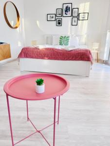 Belvárosi Stúdió Apartman في كيسكيميت: طاولة وردية اللون عليها نبتة أمام سرير