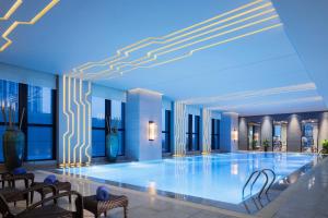 a large swimming pool in a building with chairs at Wanda Realm Jingzhou in Jingzhou