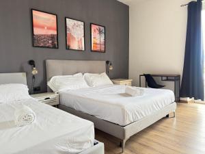 a bedroom with two beds with white sheets at Bilocale luminoso ed elegante-Parcheggio gratuito in La Spezia