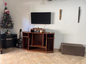 een kamer met een bureau met een televisie en een kerstboom bij Quarto privativo em casa de praia próxima a cachoeira in Bertioga