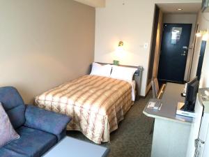Hotel Crown Hills Takaoka في تاكاوكا: غرفه فندقيه بسرير واريكه