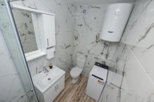 a white bathroom with a toilet and a sink at Apartment Center in Kolašin