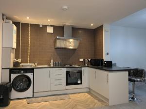 a kitchen with a stove and a washer and dryer at Modern One Bedroom Flat With Garden in Cardiff