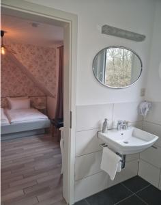 ein Badezimmer mit Waschbecken und Spiegel und einem Bett in der Unterkunft Hotel Haus Niggemann in Hattingen