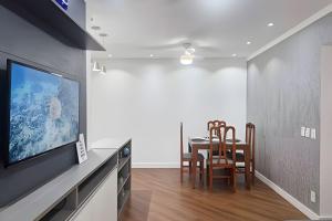 una sala da pranzo con tavolo e TV a schermo piatto di Brisa do Mar - Varanda/2 qtos/Est/Ar a Campo Grande