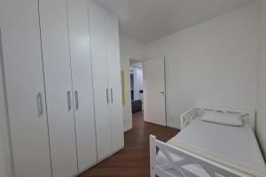 una camera bianca con armadi bianchi e un letto di Brisa do Mar - Varanda/2 qtos/Est/Ar a Campo Grande