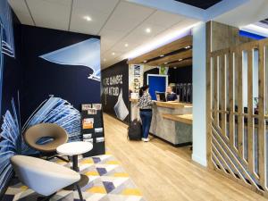 a woman standing at the counter of a store at Ibis Budget Château-Thierry in Essômes-sur-Marne