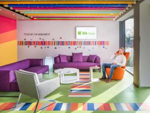 ein Mann sitzt in einem Raum mit lila Möbeln in der Unterkunft ibis Styles Budapest Citywest in Budapest