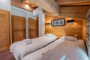 l'Ours Bleu C21 - Ski In Ski Out - Happy Rentals في فالورسين: سريرين في غرفة ذات جدران خشبية