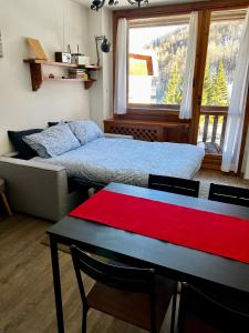 a bedroom with a bed and a table with a red blanket at da Robi appartamento fronte piste in Borgata Sestriere
