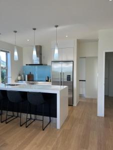 a kitchen with a large white island with black chairs at Carters Beach Retreat in Carters Beach