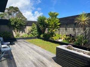 a garden with a wooden deck with a chair at Carters Beach Retreat in Carters Beach