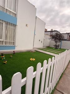 einen Hinterhof mit einem weißen Zaun und grünem Gras in der Unterkunft como en tu casa mollendo in Mollendo