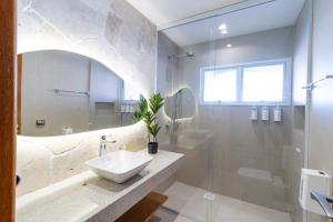 a white bathroom with a sink and a shower at Pousada Ilha Faceira in Florianópolis