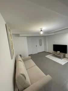 Studio proche de Paris في Valenton: غرفة معيشة مع أريكة وتلفزيون بشاشة مسطحة