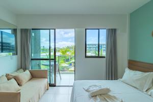 a bedroom with a bed and a couch and windows at Mana Beach Experience Muro Alto By Carpediem in Porto De Galinhas +148 photos