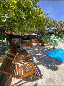 a group of wooden benches next to a swimming pool at Pousada Maruru in Serra do Cipo