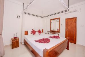 a bedroom with a bed with white sheets and a mirror at Villa Tanzanite Hikkaduwa in Hikkaduwa