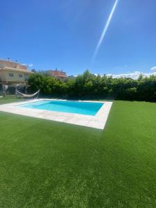 a swimming pool in a yard with green grass at Stunning Villa 25' from Barcelona in Las Canteras