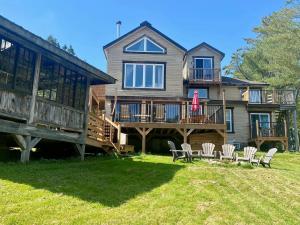 a large house with a deck and chairs in the yard at Chalets et Studios Le Vent Du Nord in Lac-Superieur