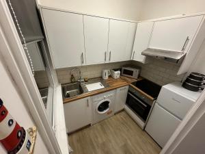a small kitchen with white cabinets and a sink at Apartment Masons Hill in Bromley