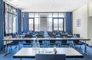 Una sala de conferencias con mesas, sillas y ventanas. en Hotel Freiburg City Center by Leonardo Hotels, en Freiburg im Breisgau