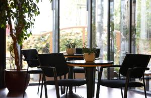 a table and chairs in a room with windows at Hotel Magdeburg City Center by Leonardo Hotels in Magdeburg