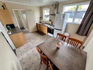 a kitchen with a table with chairs and a refrigerator at Mackenzie Cottage in Twizel
