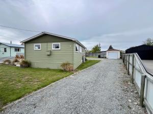 a green house on a gravel road next to a fence at Mackenzie Cottage in Twizel