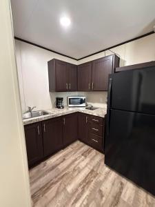 a kitchen with brown cabinets and a black refrigerator at Mesquite Oasis Lodging in Odessa