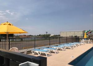 a row of chairs and an umbrella next to a pool at Mesquite Oasis Lodging in Odessa +15 photos