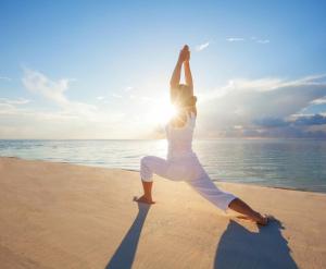 a woman doing a yoga pose on the beach at Tanjung Sari Inn in Nusa Dua