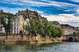 a river with buildings and trees next to a bridge at Exceptional Apartment Île Saint Louis - Jacuzzi in Paris