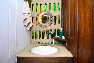 a bathroom with a sink and a wall of bottles at Hostel do Morro in Florianópolis